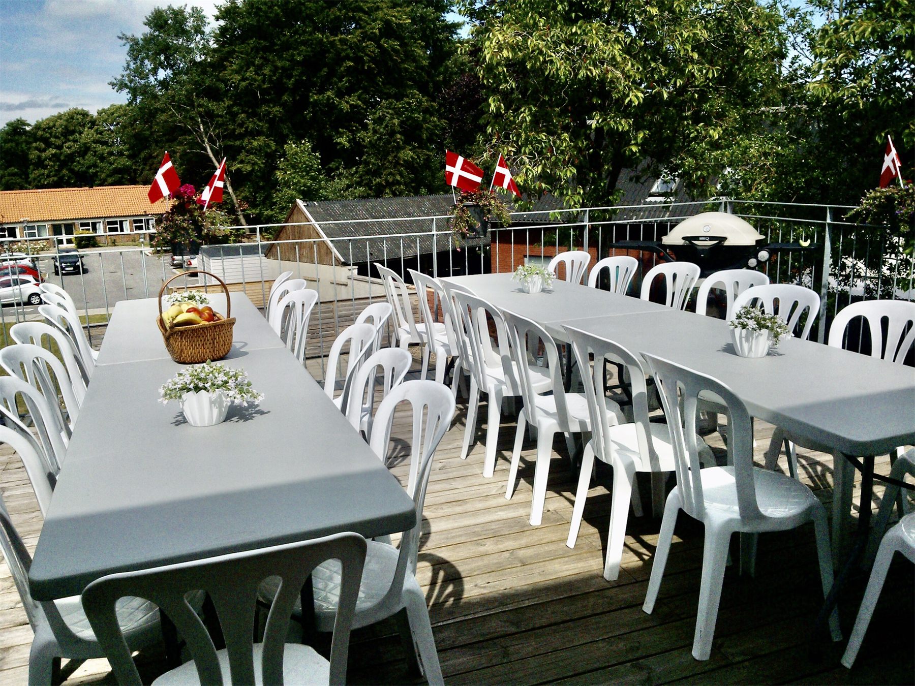 Havebord og hvide stole med flag på en terrasse